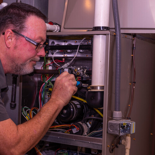 HVAC technician working inside of a furnace