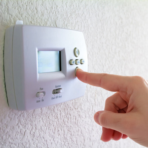 a finger pressing a digital thermostat