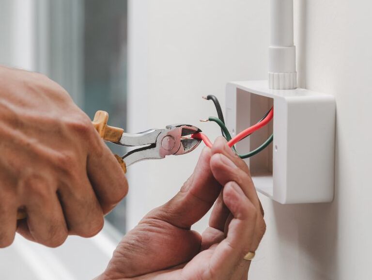 A man uses a wire cutter to work on an electrical repair.