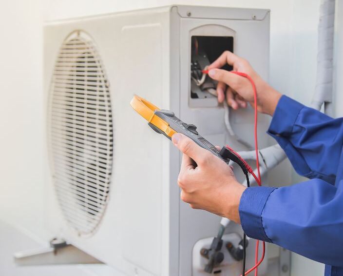 A man uses a tool to work on an AC fan.