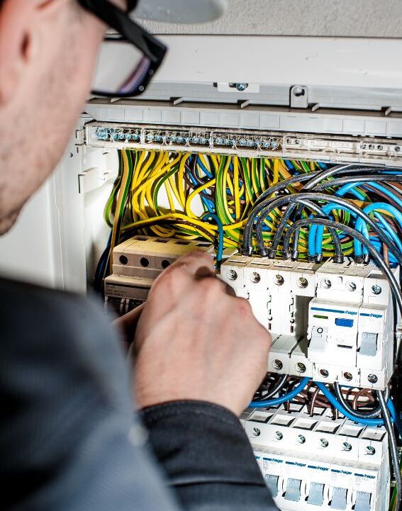 An electrician works on wires with a tool.