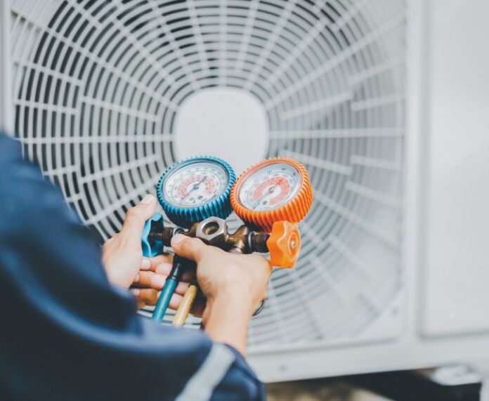 A man uses two gages to check the health of a AC unit.